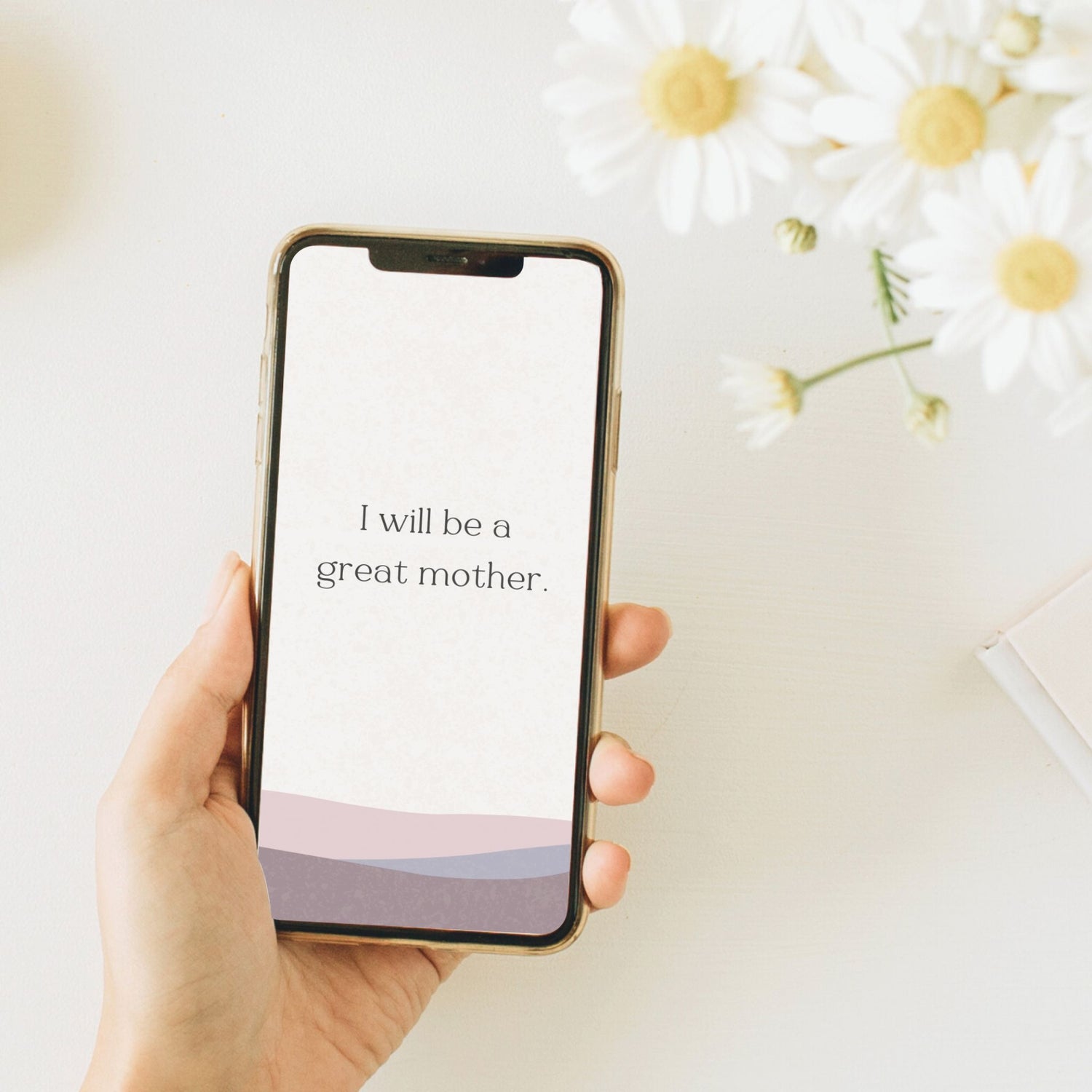 Hand holding phone displaying affirmation for pregnancy as background